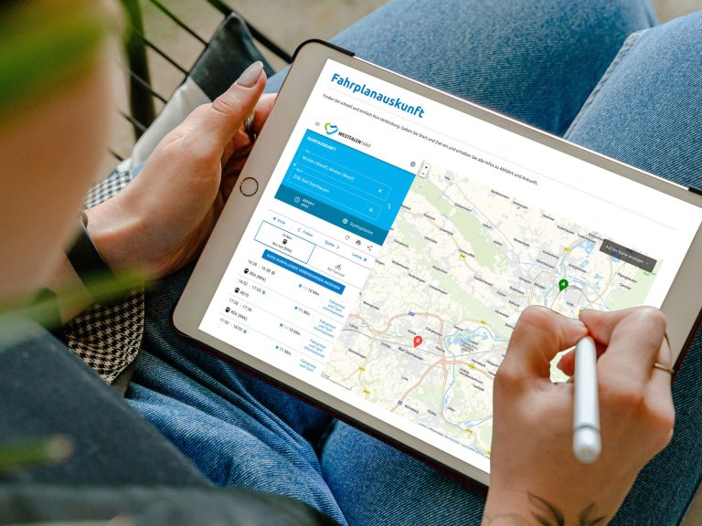 Person nutzt ein Tablet mit der digitalen Fahrplanauskunft von OWLmobil und gibt per Stift eine Verbindungssuche ein – moderne Reiseplanung mit Karte und Echtzeitdaten.