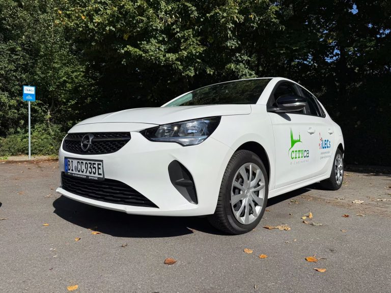 Weißes Elektrofahrzeug mit CITYca- und LEC-Logo steht auf einem Parkplatz im Grünen – Teil des interkommunalen Linien-eCarsharings in Borgholzhausen und Künsebeck für flexible Mobilität auf der letzten Meile.
