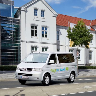 Ein flex-taxi-Fahrzeug steht vor dem modernen Rathaus in Verl – flexible und wohnortnahe Mobilität mit OWLmobil.